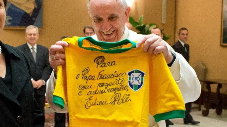 Papa Francisco segura camisa da seleção brasileira autografada pelo Rei Pelé. Na camisa é possível ler: Papa Francisco, com respeito e admiração Edson Pelé.